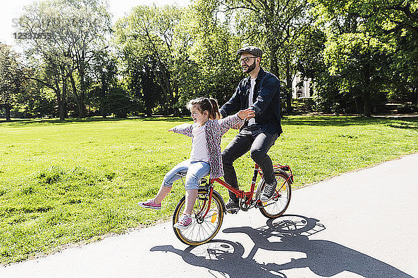 Happy father riding bicycle with daughter in a park