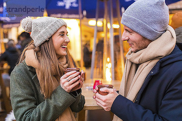 Happy young couple drinking mulled wine at Christmas market
