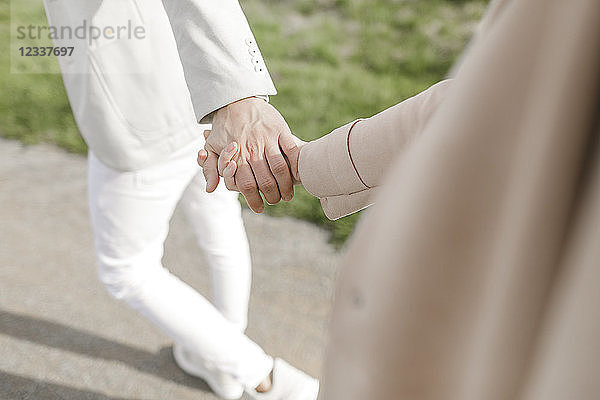 Strolling young copule holding hands  partial view