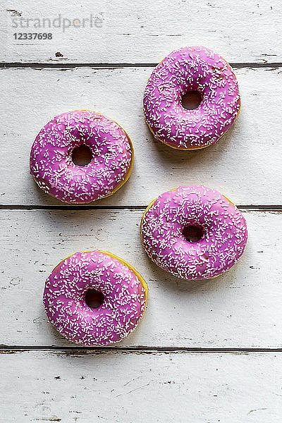 Four pink doughnuts on white wood