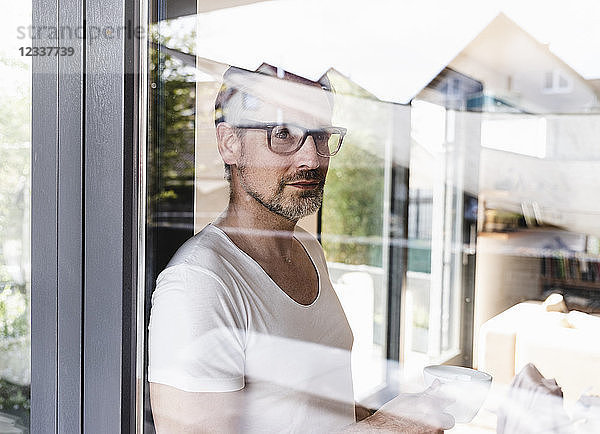 Portrait of pensive man standing behind glass door