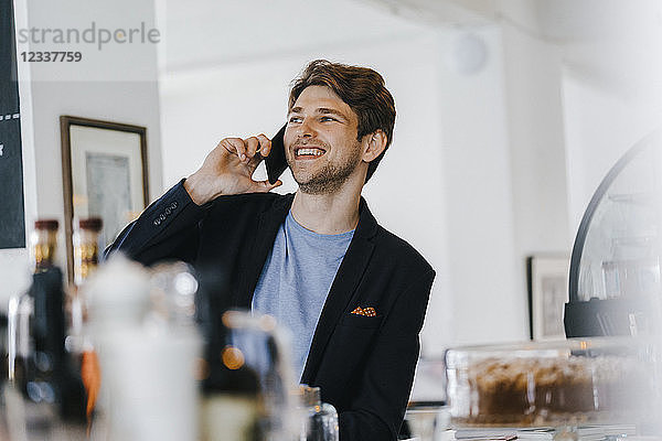 Smiling man in a cafe talking on cell phone