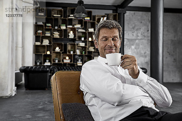 Portrait of mature man enjoying cup of coffee in loft