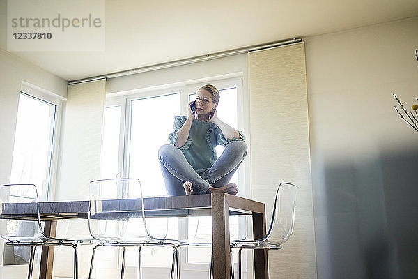 Businesswoman on the phone sitting barefoot on meeting table