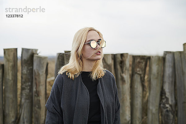 Portrait of blond young woman wearing mirrored sunglasses on the beach