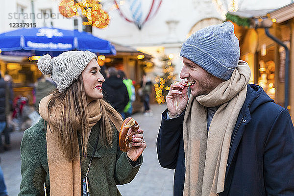 Young couple eating pretzel together at Christmas market