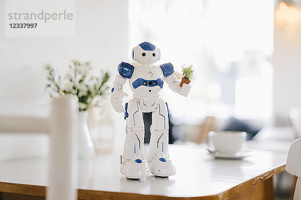 Miniature robot figurine holding flowerpot