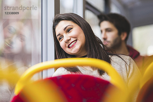 UK  London  portrait of smiling young woman in bus looking out of window