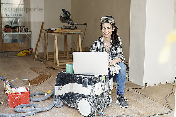 Young woman renovating her new flat  using laptop