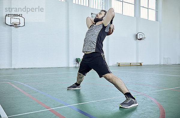 Man with basketball  stretching  indoor