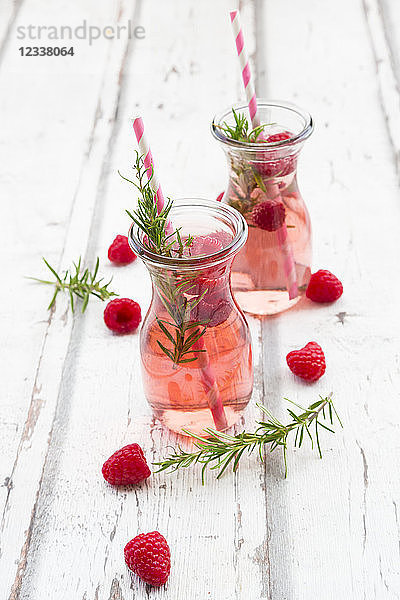 Two glass bottles of homemade raspberry lemonade flavoured with rosemary