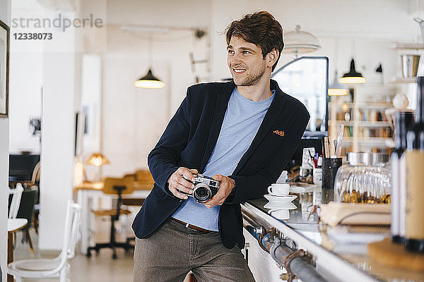 Smiling man in a cafe holding camera