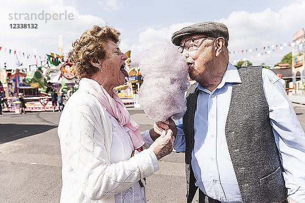 Senior couple on fair eating together cotton candy