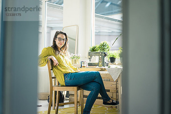 Portrait of fashion designer sitting at desk in her studio