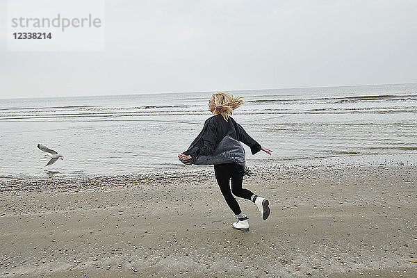 Netherlands  happy blond young woman running on the beach