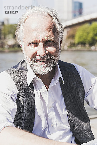 Portrait of smiling mature businessman at the riverside