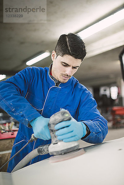 Man polishing the hood of a car in a workshop
