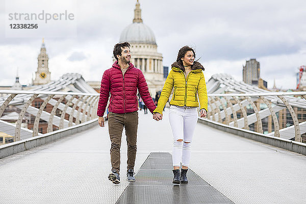 UK  London  young couple walking hand in hand on bridge in front of St Pauls Cathedral