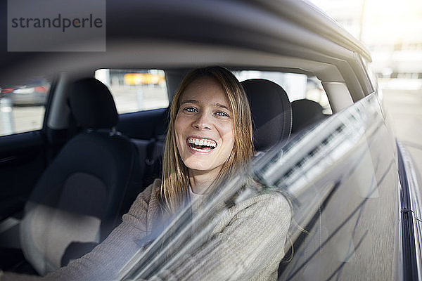 Portrait of laughing young woman sitting in car