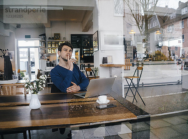 Man sitting at table in a cafe with laptop