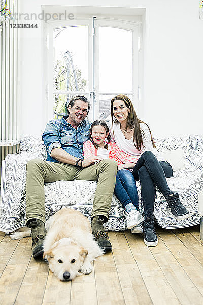 Portrait of happy family with dog in living room
