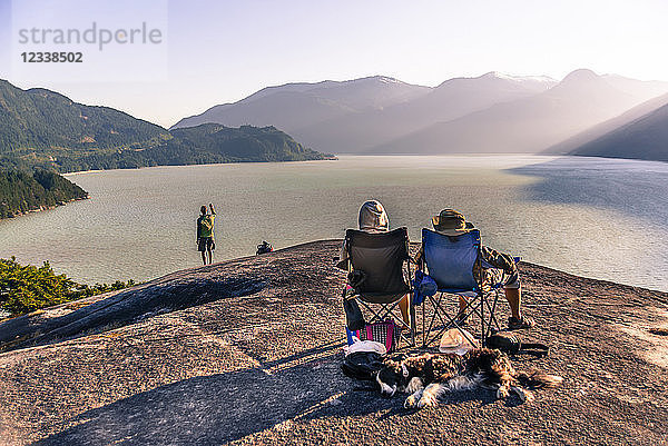 Freunde entspannen sich in Campingstühlen auf einem Bergsims mit Blick auf den See  Squamish  Kanada