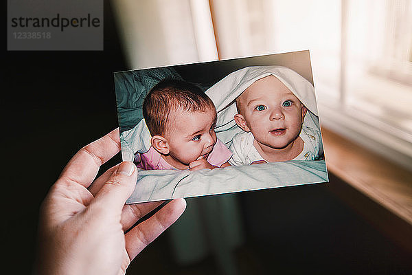 Mutter hält Foto von Zwillingsbaby Mädchen und Junge  Nahaufnahme der Hand  persönliche Perspektive