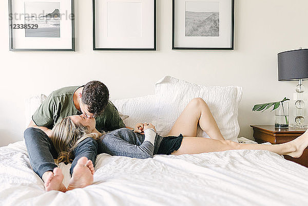Paar entspannt im Bett  küsst sich