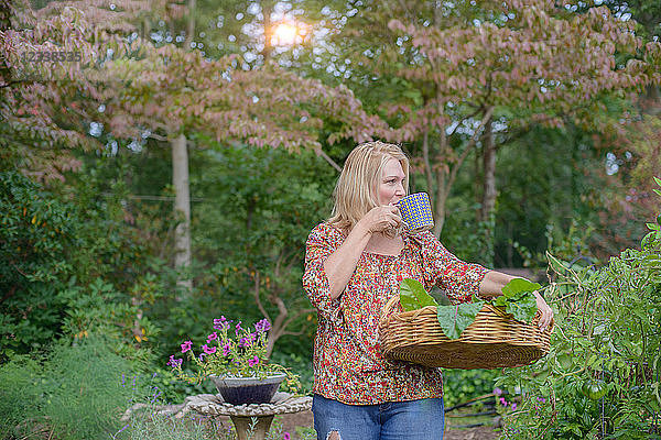 Frau im Garten trinkt aus Tasse