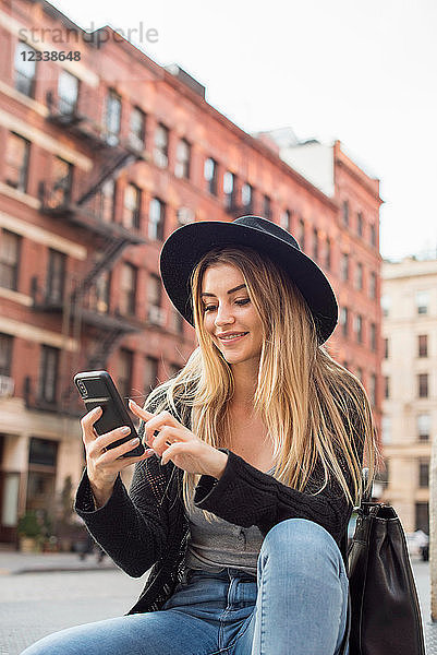 Frau schaut lächelnd auf Handy  schreibt SMS  New York  USA
