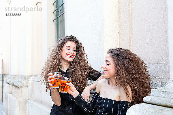 Mode-Blogger-Zwillinge stoßen mit Cocktail auf das Gebäude an