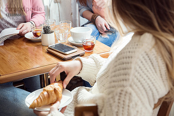 Frauen unterhalten sich bei Kaffee und Croissant im Café