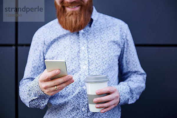 Bärtiger Mann textet auf Smartphone  abgeschnitten