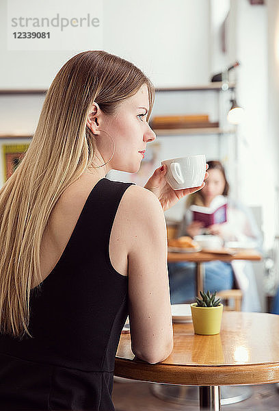 Junge Frau beim Kaffeetrinken im Café
