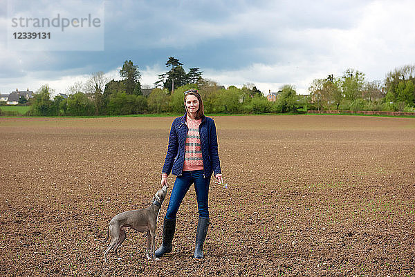Mittlere erwachsene Frau und Whippet-Hund im Feld  Porträt