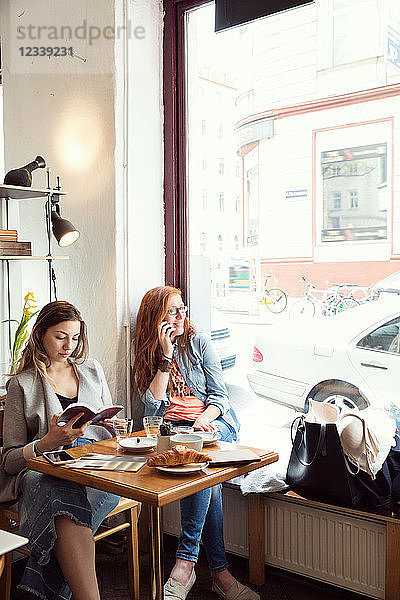 Frauen lesen und plaudern am Handy im Cafe
