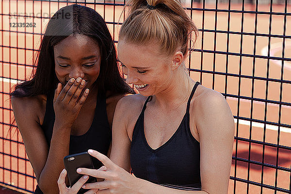 Junge Frauen lächeln  lesen Texte auf dem Handy