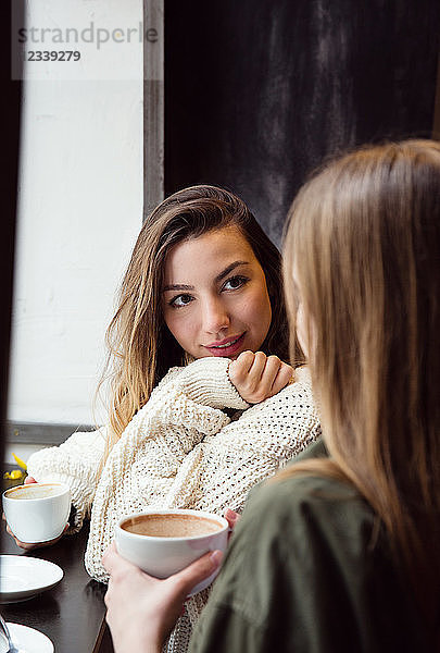 Junge Frauen unterhalten sich bei Kaffee im Café