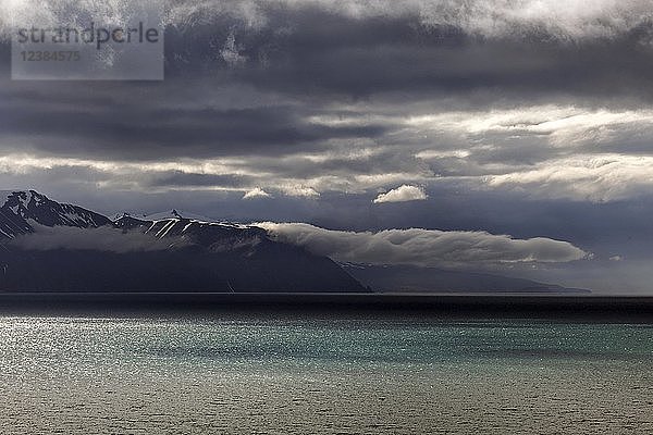 Lichtstimmung mit dramatischen Wolken über dem türkisfarbenen Meer  Skjalandi-Fjord  nahe Husavik  Nordisland  Island  Europa