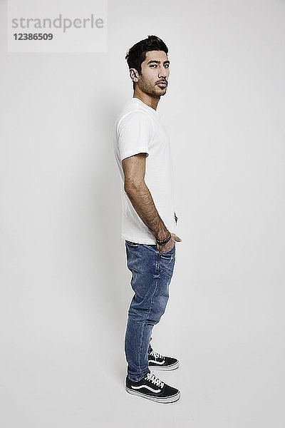 Junger Mann  weißes T-Shirt  Jeans und Turnschuhe  Studioaufnahme