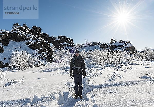 Mann auf Wanderweg im Schnee bei Sonnenschein  verschneite Landschaft  verschneites Lavafeld  Vulkanlandschaft Krafla  Dimmuborgir Nationalpark  Mývatn  Island  Europa