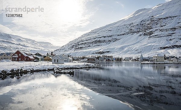 Blick über das Dorf Seyðisfjörður mit Schnee  Spiegelung im See Fjarðará  Austurland  Ostisland  Island  Europa