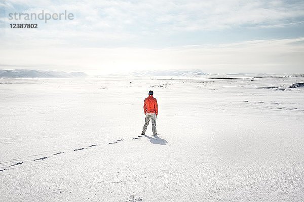 Junger Mann steht allein in verschneiter Landschaft  verschneite Lavafelder in der Nähe des Dettifoss  Norðurland eystra  Island  Europa