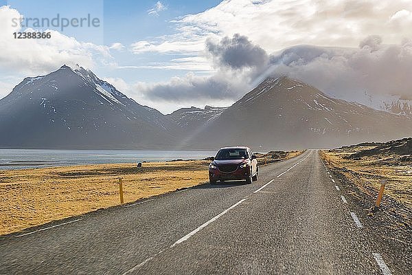 Auto auf Ringstraße  Landstraße am Meer  zerklüftete Vulkanlandschaft mit Bergen  Island  Europa