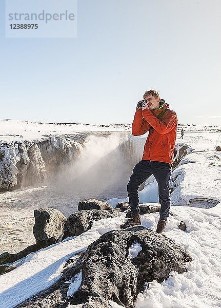 Fotografieren eines Mannes am Selfoss-Wasserfall im Winter  Schlucht  Nordisland  Island  Europa