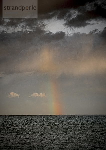 Regenbogen mit dunklen Wolken über dem Meer  dramatische Atmosphäre