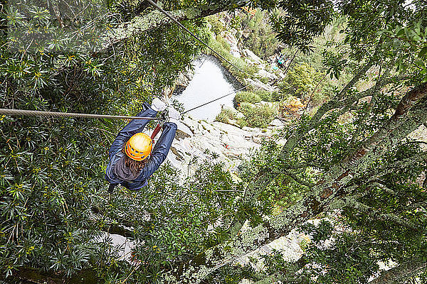 Woman zip lining among trees in woods