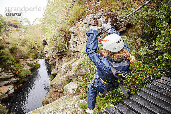 Woman zip lining over pond in woods