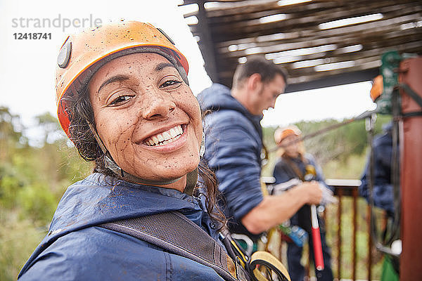 Portrait enthusiastic  muddy young woman enjoying zip lining