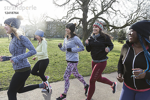 Female runners running in sunny park